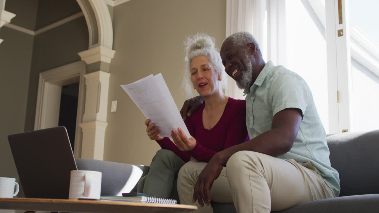 Mixed race senior couple discussing finances together in the living room at home