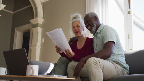 mixed race senior couple discussing finances together in the living room at home