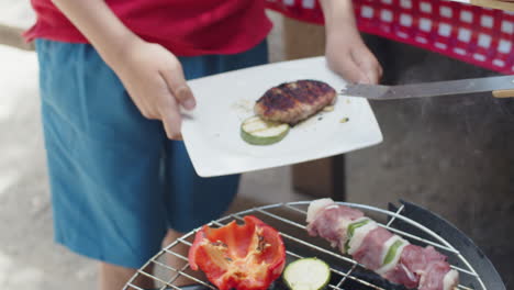 tracking shot of an unrecognizable person putting grilled meat on plate