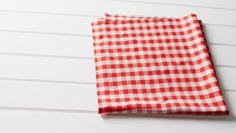 close up of folded red and white checkered blanket on white background with copy space