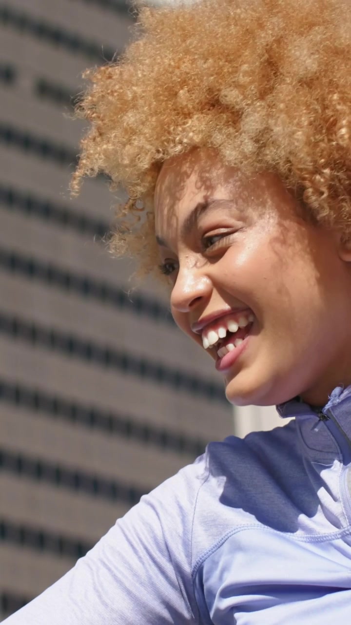Vertical video: Laughing woman reacting to sunlight, turning on rooftop with lavender top, tower