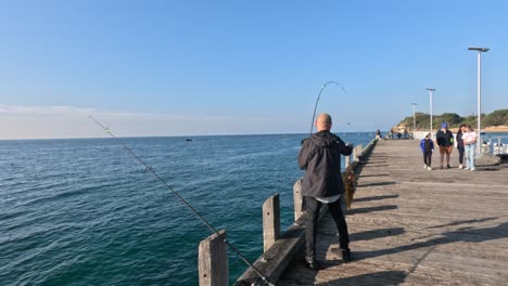 man fishing on pier with others walking