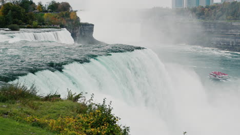 the famous niagara falls is a landmark of the state of new york and america. in the distance on the river floats a boat with tourists