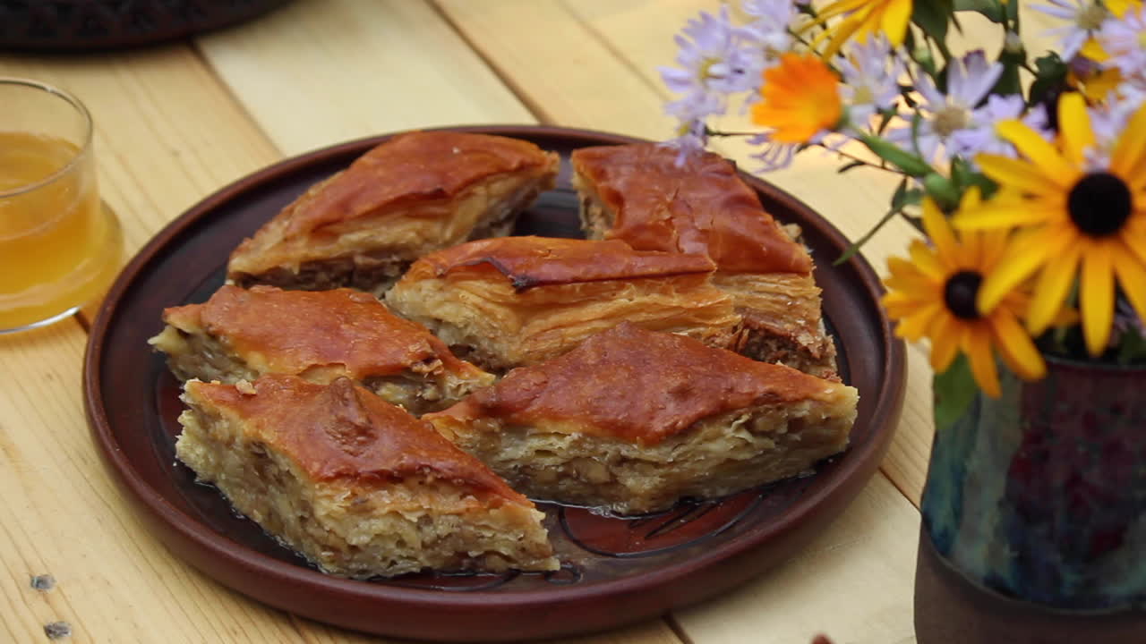 Baklava caseira na mesa ao lado de uma garrafa com flores