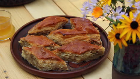 homemade baklava on table next to bottle with flowers