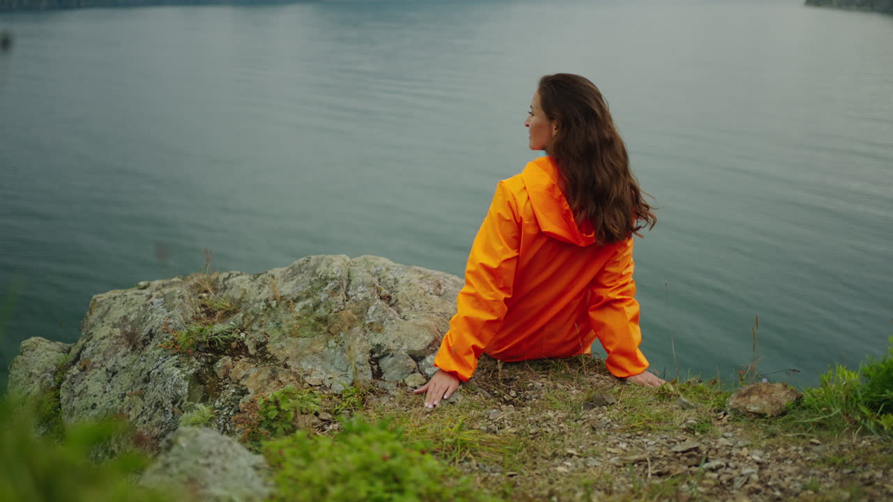 Woman sitting on a cliff overlooking a lake