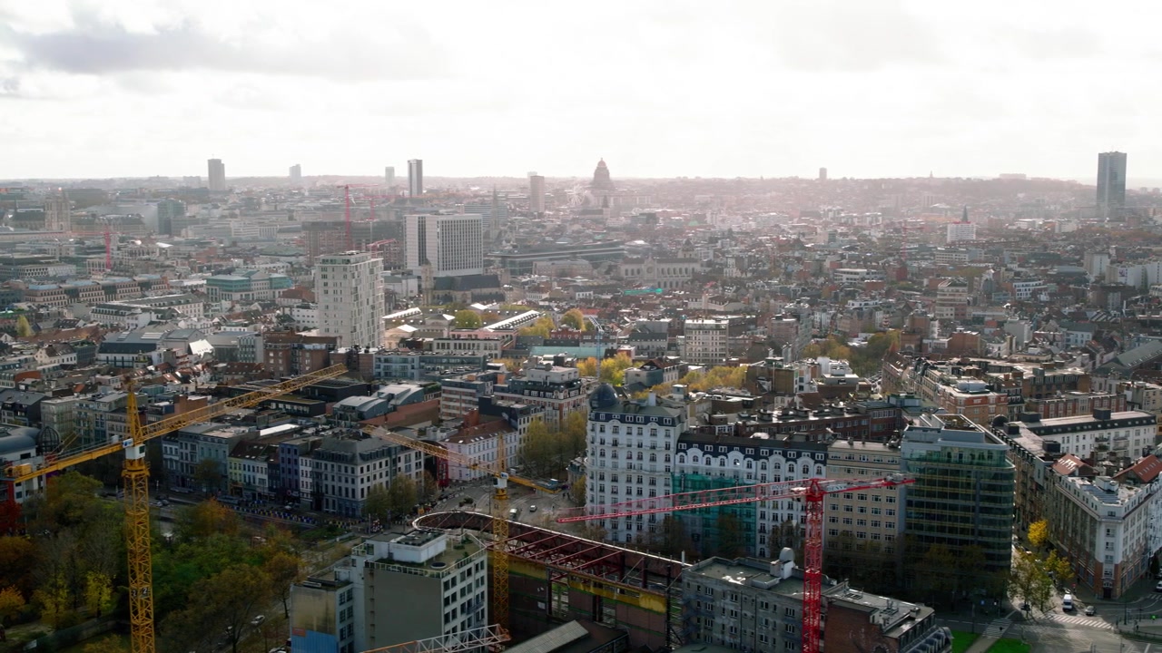Rekaman drone menunjukkan gambaran luas kota Brussels, dengan cakrawala perkotaan, bangunan, dan lanskap kota di bawah langit yang sebagian cerah.