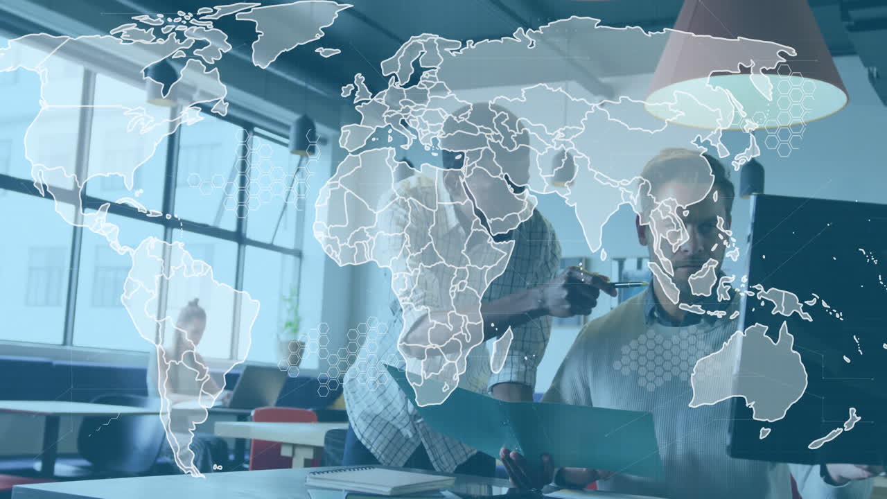 IT professionals pointing at computer monitor in office, showing floating world map overlay