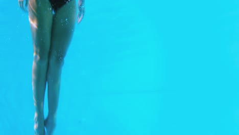 pretty brunette swimming underwater into pool with snorkel