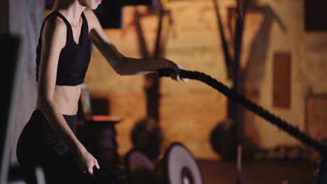 Attractive-Young-Fit-Female-Athlete-Exercising-With-Battle-Ropes-During-Cross-Training