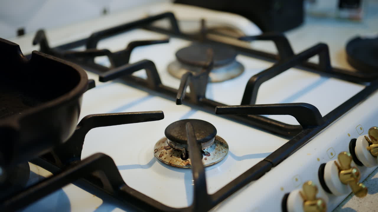 Close-up van een vrouw die een gasfornuis schoonmaakt, met een gietijzeren pan op de brander.
