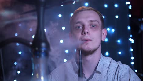 hombre fumando narguile en un club nocturno