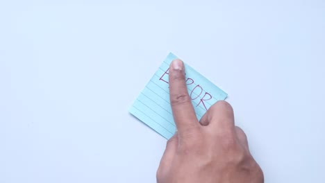 hand holding a light blue sticky note with the word error written on it.