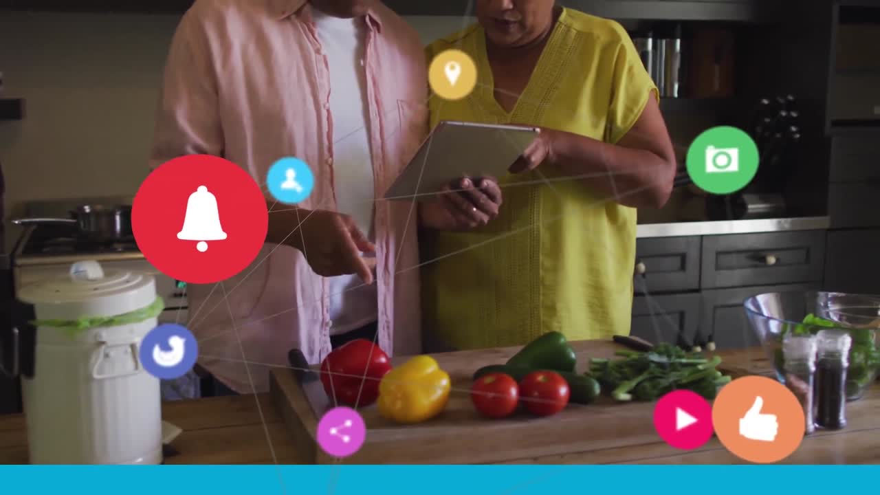 red de iconos digitales contra una pareja mayor que usa tableta digital en la cocina en casa