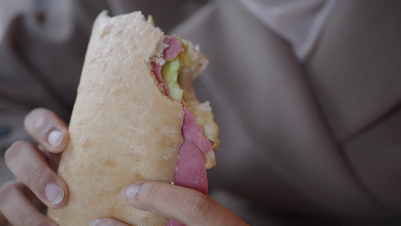 Gros plan d'une personne mordant dans un délicieux sandwich de traiteur