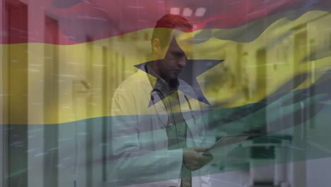 Animation-of-waving-ghana-flag-against-caucasian-male-senior-doctor-using-digital-tablet-at-hospital