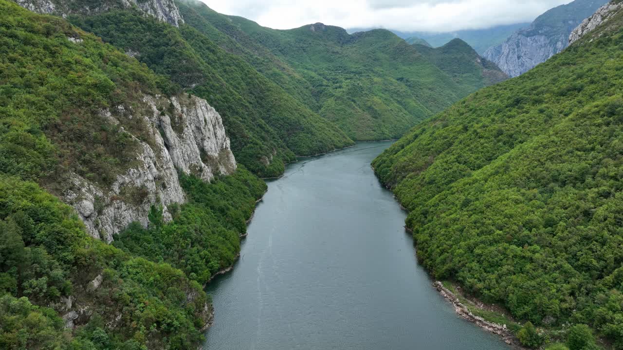 Aerial pullback along gorgeous waters of Lake Koman, Albania, surrounded by towering cliffs, establishing