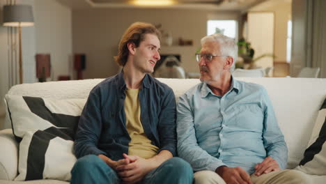 father and son talking on couch
