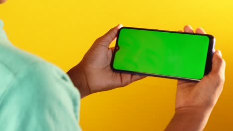 person holding a smartphone with a green screen