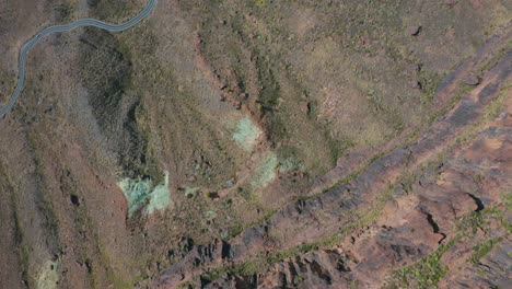 toma de arriba hacia abajo de un dron de una montaña y una calle curva con autos