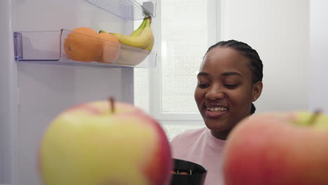 woman taking salad bowl from the fridge