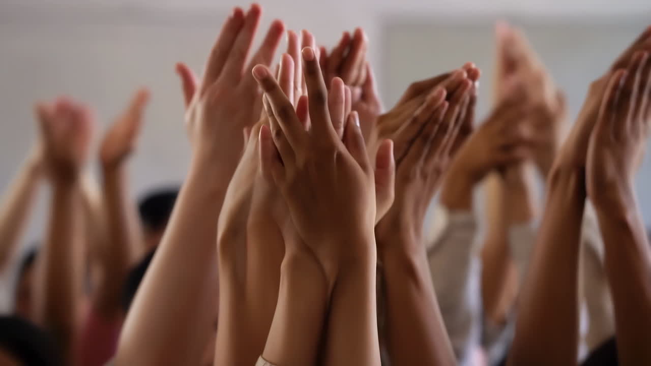 A crowd of people with hands raised in applause or celebration