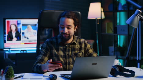 happy man doing internet shopping, typing credit card information on laptop