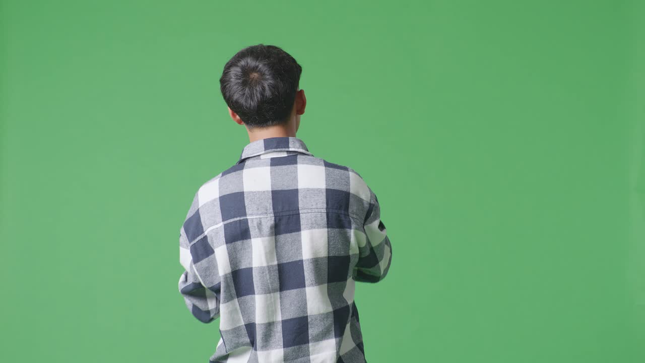 녹색 스크린 배경에서 마이크를 들고 노래하는 젊은 아시아 십대 소년의 뒷면