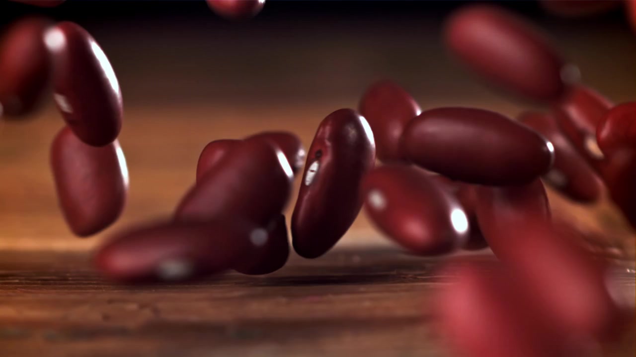 Close-up of Red Kidney Beans Falling onto a Rustic Wooden Table