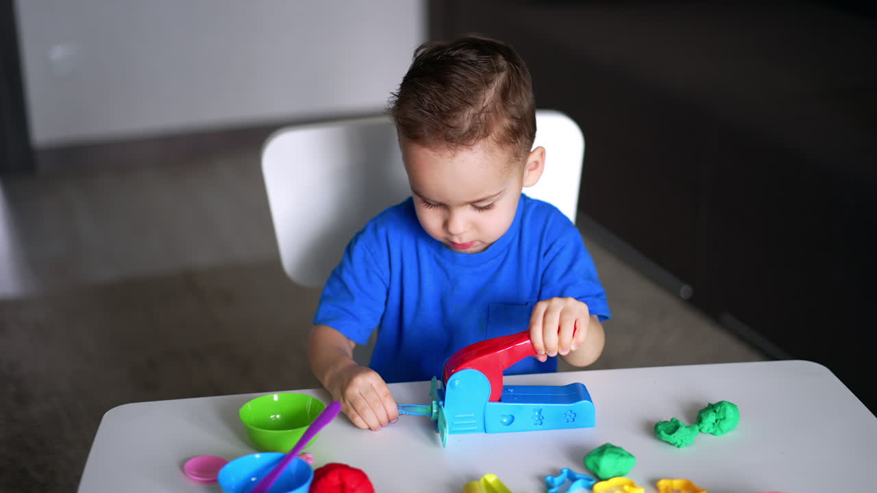 Sweet baby boy using a device to play with plasticine. Toddler kid practicing sculpturing at home.