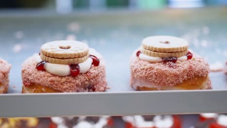 vista de cerca de las rosquillas cubiertas con tapa rosa y galletas en una panadería