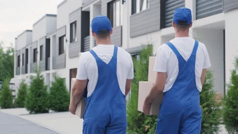 two young workers of removal company deliver boxes to a customer's home