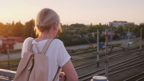 lonely woman stands at the railing of the bridge looks at the railway