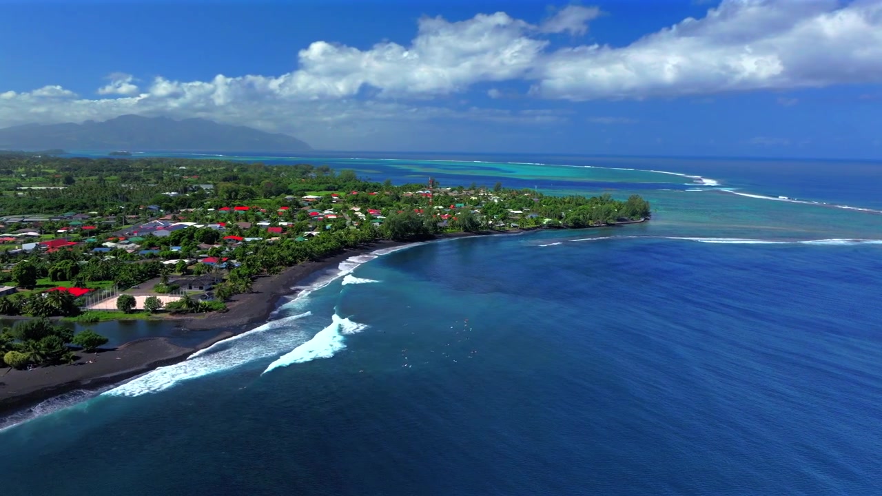 Surfisti Spiaggia di Taharuu spiaggia di sabbia nera vulcanica paesaggio costiero di Tahiti Polinesia Francese drone aereo Papeete surfspot di Vaira'o Oceano Pacifico Meridionale onde mattina soleggiata cielo blu edifici a cerchio
