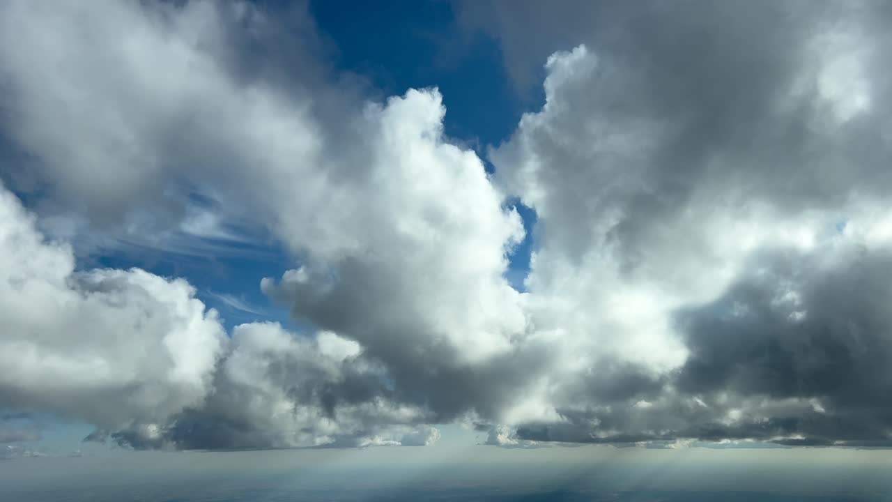 Immersive pilot POV flying under some white frayed clouds in a real time flight in a deep blue sky at golden hour