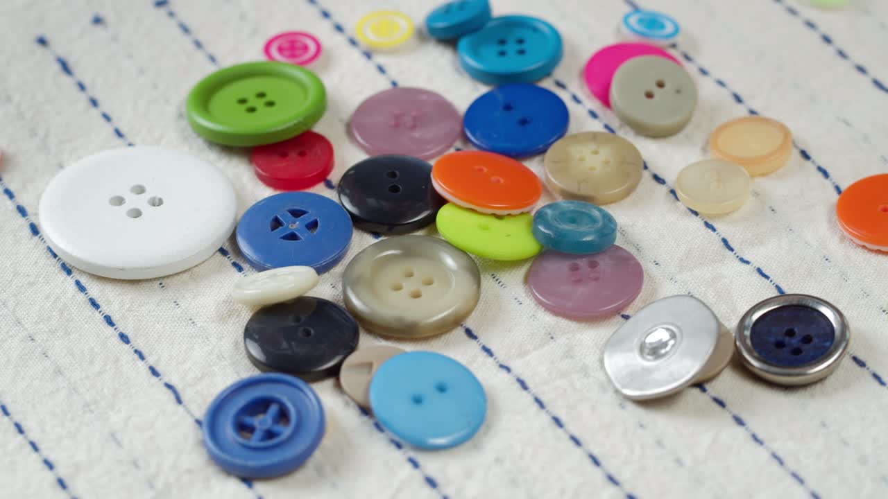 botones coloridos que caen en la tela a rayas de primer plano. confección de ropa y concepto de costura profesional. elección de accesorios de botones para el material