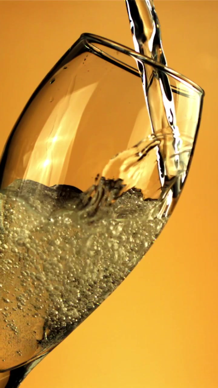 Champagne dorato versato in un bicchiere a flûte con bollicine effervescenti.