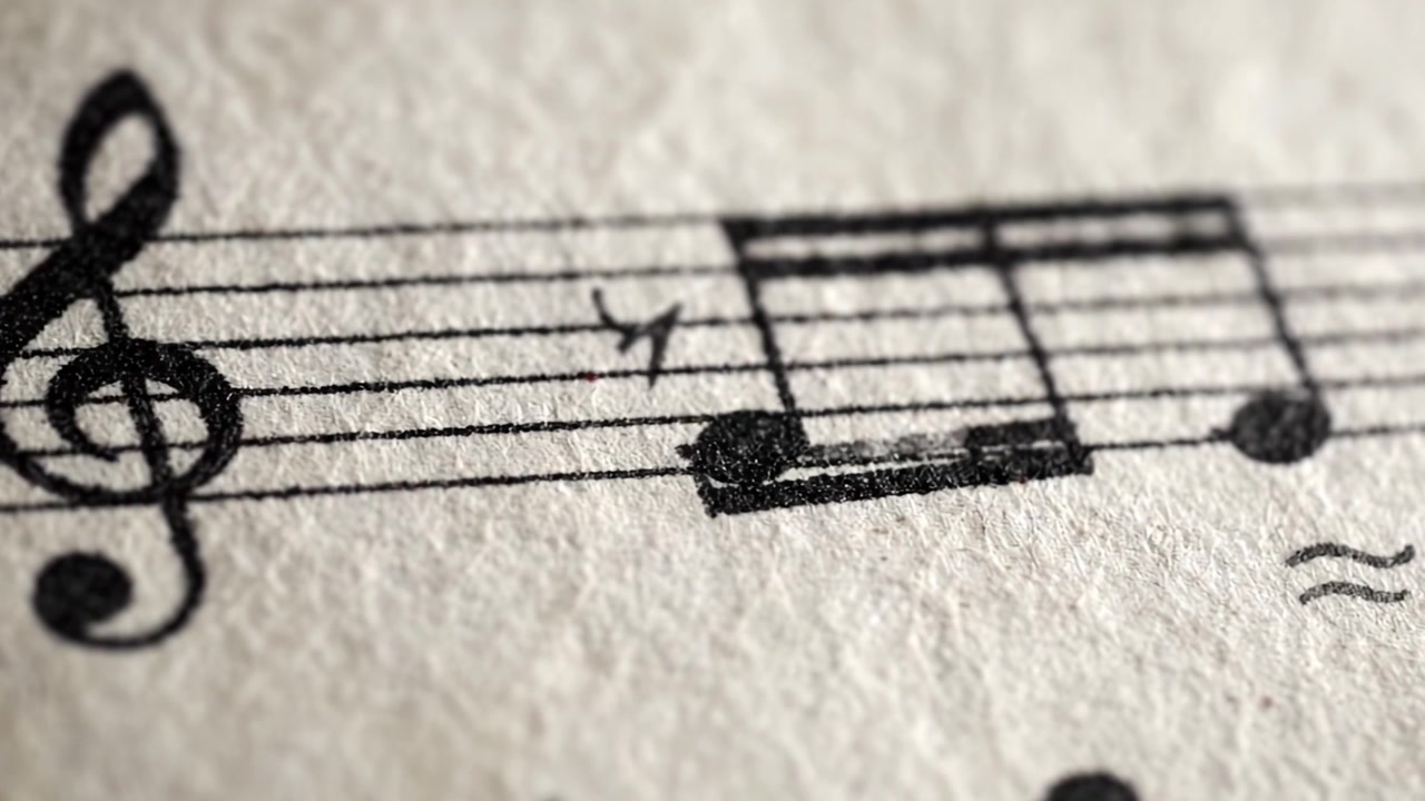 Primo piano di notazione musicale: una vista dettagliata di uno spartito con varie note catturate in due fotogrammi, evidenziando l'arte della composizione musicale.