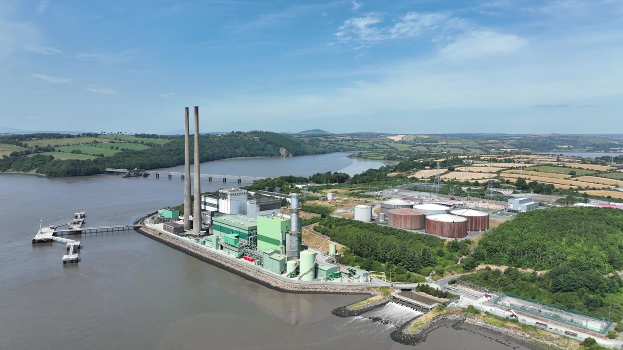 Volo drone cinematografico fluido sopra una centrale elettrica fluviale nella contea di Wexford con vista sull'estuario del fiume Suir