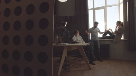 three stylish and proactive young modern professionals having a funny conversation in a radio studio before or after recording