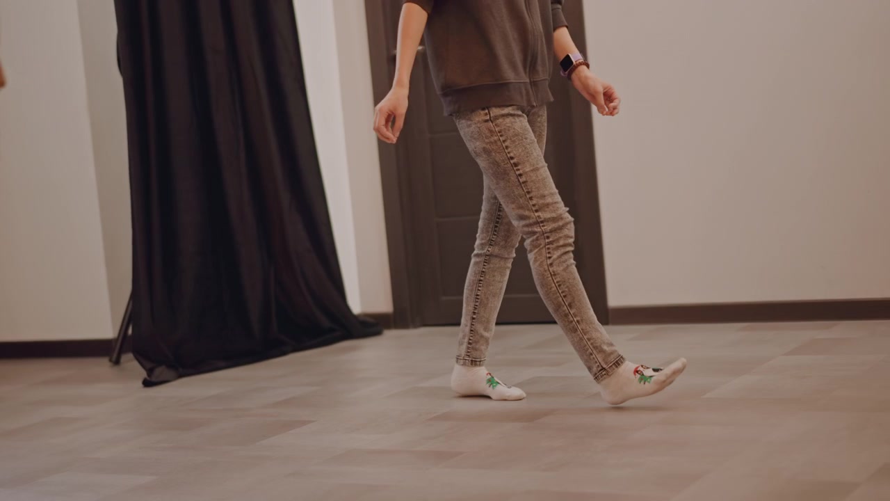 Caucasian students practicing footwork across studio floor, patterned pants and sneakers, choreographerled repetition focusing on timing and stride, casual rehearsal vibe with neutral lighting