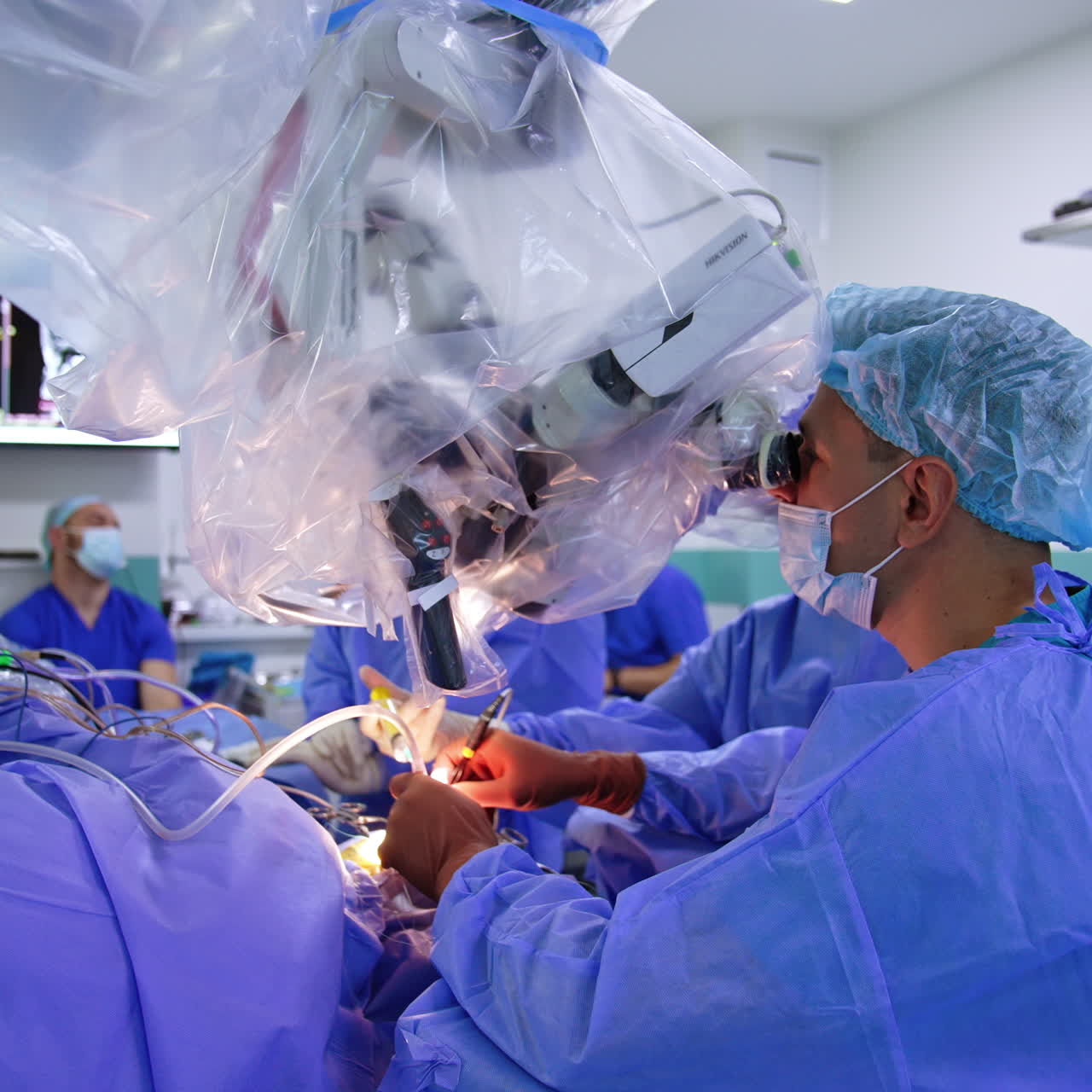 Professionel mandlig neurokirurg opererer patienten og kigger i mikroskopet. Moderne hjernekirurgi på hospital.