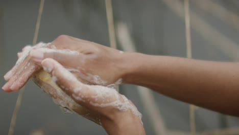 woman washes hands with soap by river with plants and reeds