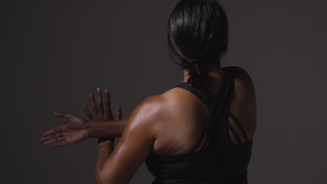 Close-Up-Studio-Shot-Showing-Back-Of-Mature-Woman-Wearing-Gym-Fitness-Clothing-Doing-Stretching-Exercises-3