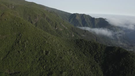 Aerial-shot-over-Madeira-island-with-clouds-dancing-around-the-mountain-and-valley-in-the-distance