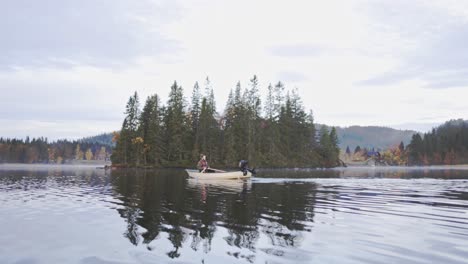 man paddles boat into the river with islet in background in norway