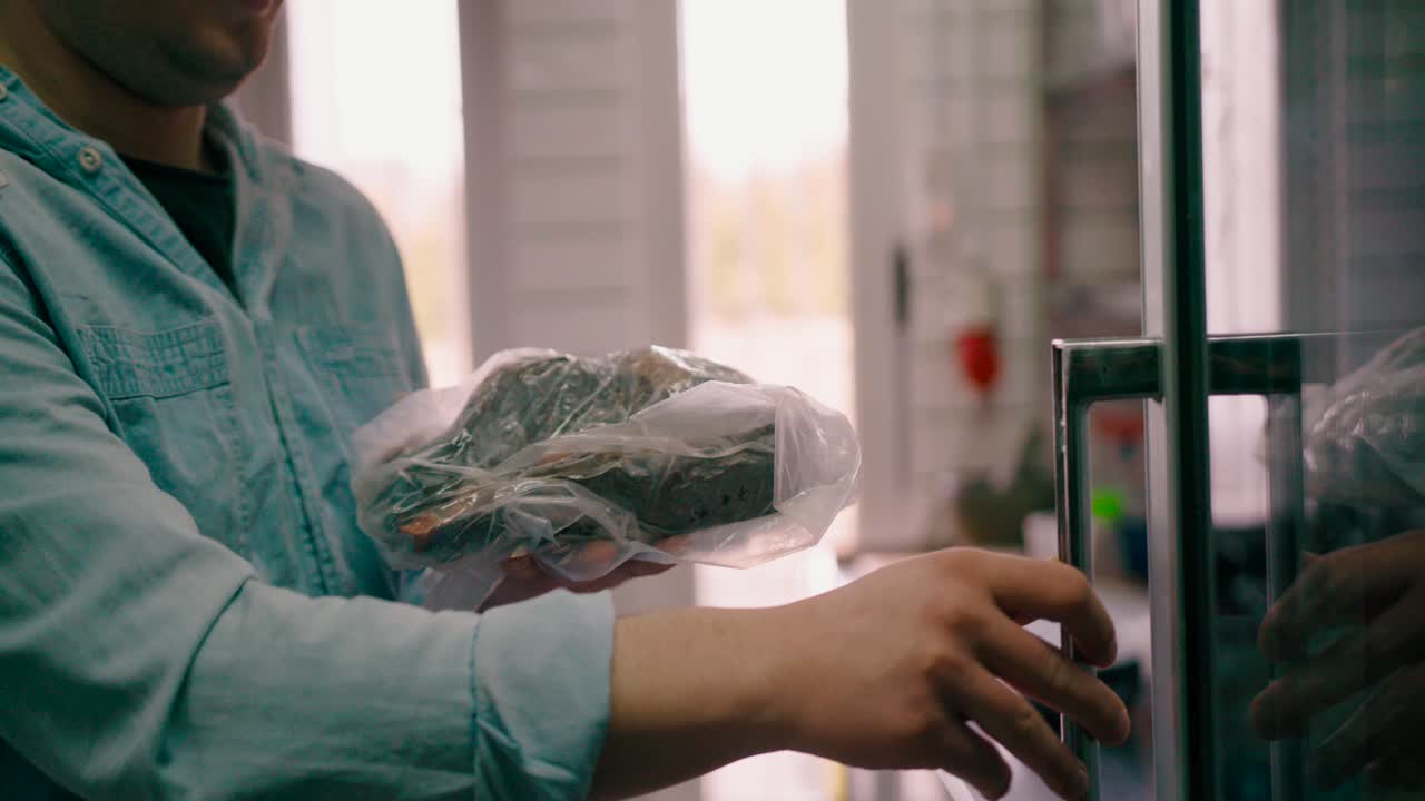 hombre sacando el filete congelado sellado al vacío del refrigerador