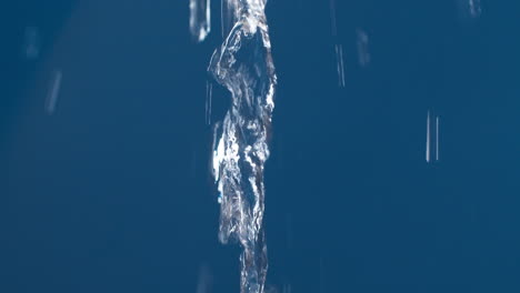 real pure water flowing down with splashing on blue background shooting in slow motion