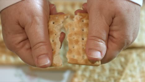 close up of female hands breaking a cracker in half