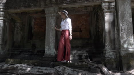 beautiful woman walking through ancient ruins of old stone temple in cambodia